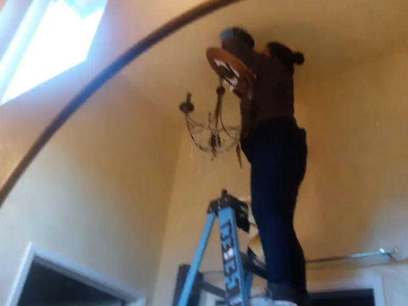 Electrician installing a chandelier in a Rincon Valley residence